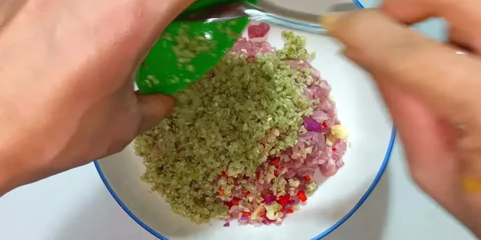In a bowl, combine the chopped garlic, shallots, chili peppers, ground lemongrass, ground pepper, MSG, sugar, and shrimp paste with the ground pork.