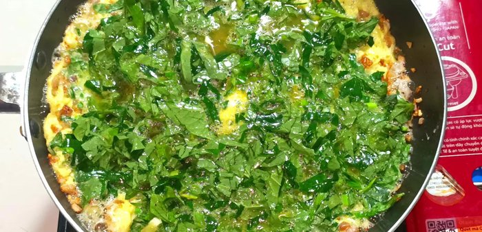 Once the egg surface is slightly dry, reduce heat to low, cover the pan, and cook until the eggs are set and the leaves are wilted.