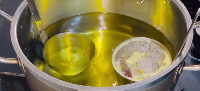 Carefully place the mold into the hot oil, ensuring it doesn't submerge completely. Fry for 5-10 seconds, then fully submerge to prevent overflowing. Fry until golden brown and crispy.