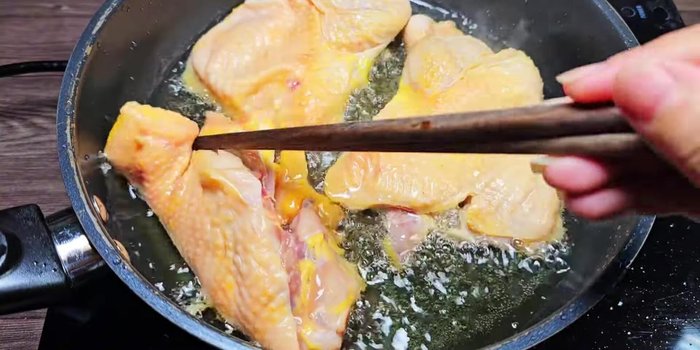 Fry chicken pieces in a pan with cooking oil until lightly golden.