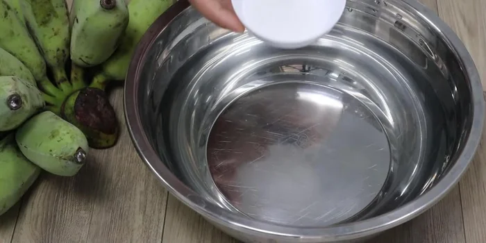 Prepare salt and lemon water: Mix salt and squeezed lemon juice in a basin of water. This helps prevent the bananas from turning black.