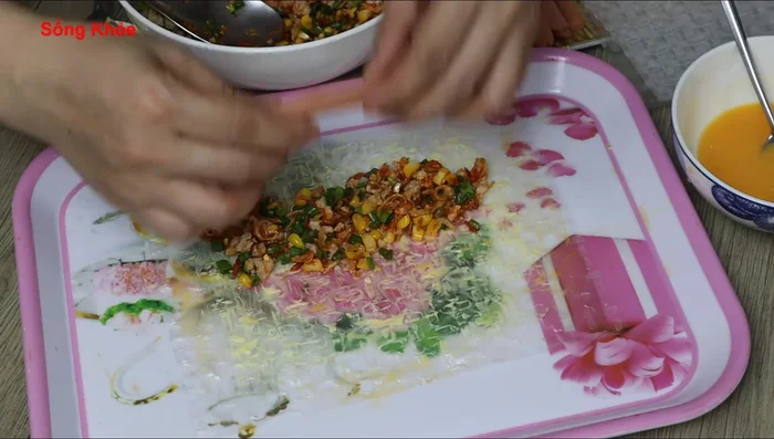 Add a spoonful of filling and a sausage to each rice paper. Roll up tightly, sealing the edges with the egg.