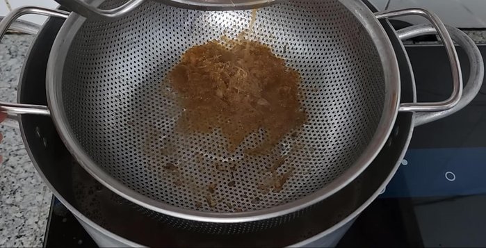 Filter the fish sauce broth into another pot, reserving the bones. Add 1 liter of coconut water.