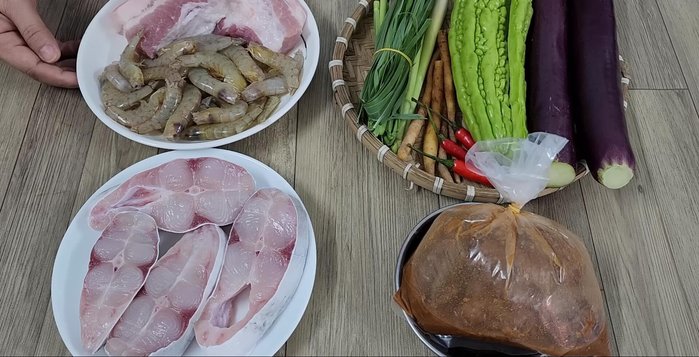 Wash and drain the pork belly, shrimp, snakehead fish, lemongrass, wormwood, chili peppers, bitter melon, and eggplants.