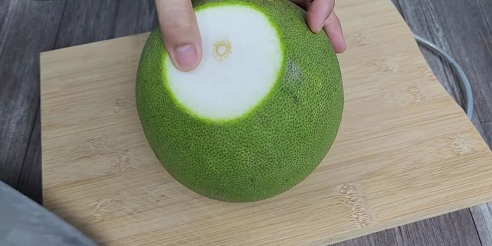 Peel the pomelo, removing the green skin and separating the white pulp.
