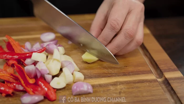 Mince shallots, garlic, and chili peppers. Crush them in a mortar with ginger.