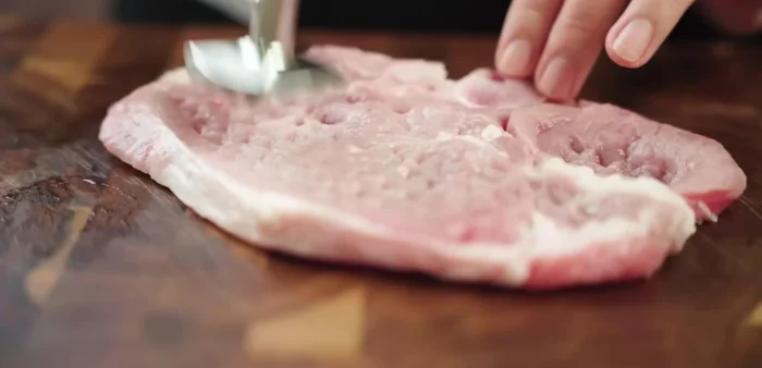 Wash and dry pork chops completely. Press the meat to make it softer and cut tendons to prevent shrinkage during grilling.