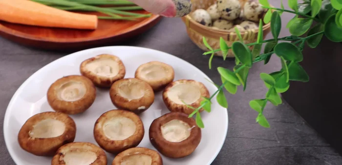 Crack and peel 10 quail eggs, then place them inside the prepared mushrooms.