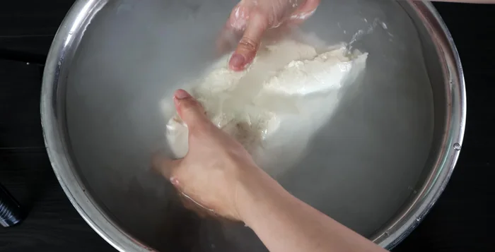 Wash the dough repeatedly in a basin of water, gently squeezing to remove excess flour until the water runs clear. Repeat 4-5 times.