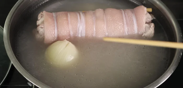 After an hour, turn off the heat and remove the pork leg. Prepare a bowl of ice water and immerse the pork leg to cool quickly and retain crispness. Let it cool for 15 minutes.