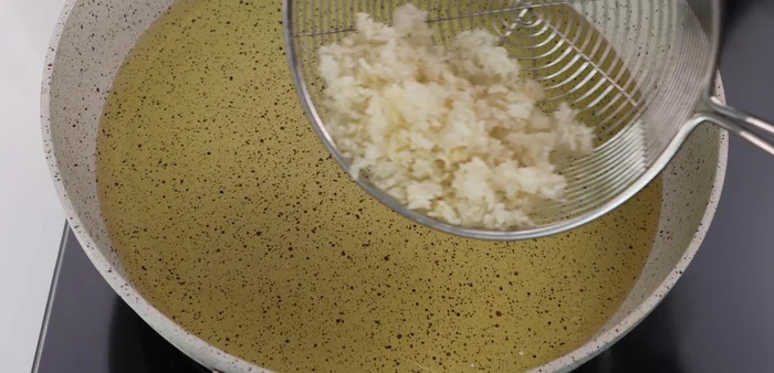 Add the dry rice to the hot oil, stirring constantly with chopsticks to ensure even puffing. Maintain moderate heat.