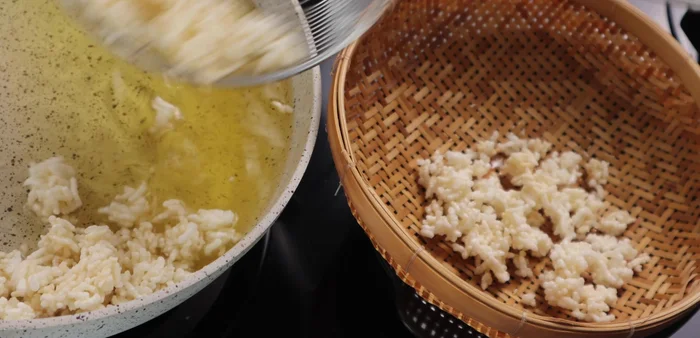 Scoop the fried rice into a basket to drain excess oil.