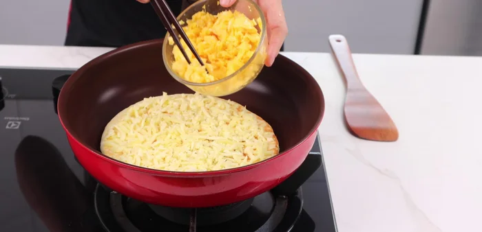 Add cheese and cooked egg mixture to the pizza.