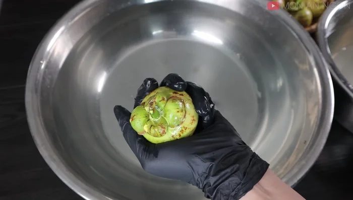 Peel the mangosteens under water (in the lemon-salt solution) to minimize water waste. Remove the head and tail, then peel the thick skin, keeping the fruit submerged.