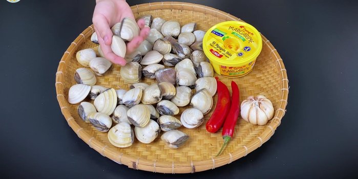 Prepare 1.5 kg of clams. Soak clams in diluted salt water with 2-3 chili peppers for 5 minutes to release sand.