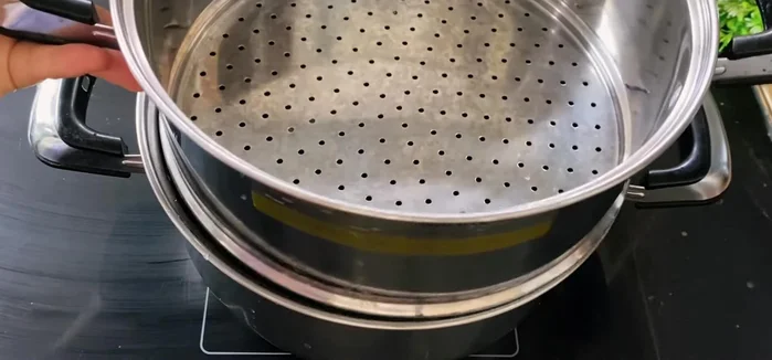Steam the sticky rice: Place a few pandan leaves in the steamer. Steam the sticky rice mixture for 15-20 minutes, then stir and steam for another 5-10 minutes. Then add 300 ml coconut milk, a tablespoon of coconut oil, and stir it.