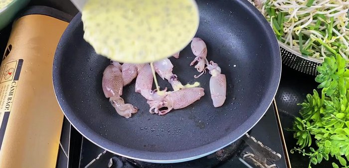 Cook the pancakes: Heat the pan with pork fat. Add squid and stir briefly. Add a scoop of batter with mussels. Cover for 30 seconds. Add bean sprouts and chives. Spread oil around the edges for crispier pancakes (370.8).