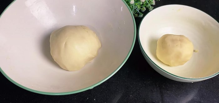 Assemble the mooncakes: Divide the dough into 14 parts. Roll out a dough ball, flatten, place an oil dough ball on top, wrap and seal. Repeat with all dough balls. Let rest for 30 minutes.