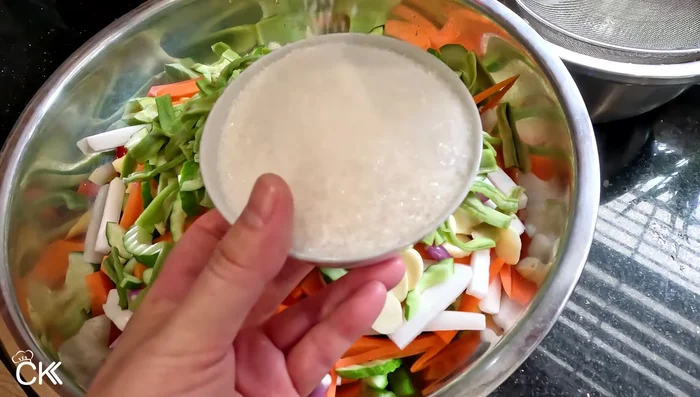 Add sugar (2 cups), salt (1/5 cup), and mix well. Cover and refrigerate overnight to wilt the vegetables.