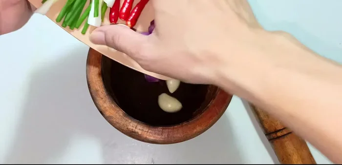 Pound garlic, shallots, and chili peppers in a mortar until smooth (45.96).