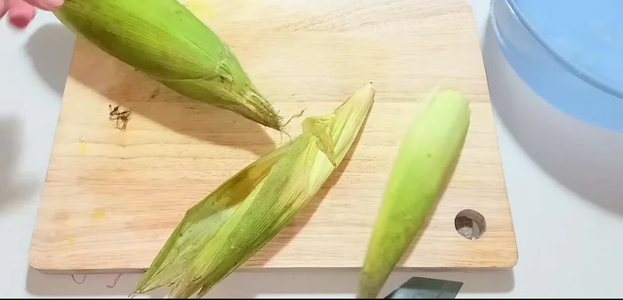 Cut off the corn stalks and base. Peel off the old outer shell, keeping the fresh inner shell.