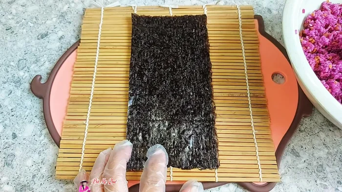 Cut seaweed sheets to the length of the cucumber. Spread a thin layer of rice evenly on the seaweed, pressing to adhere.