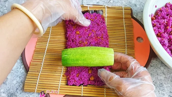 Place a cucumber strip in the center of the rice-covered seaweed. Roll tightly.