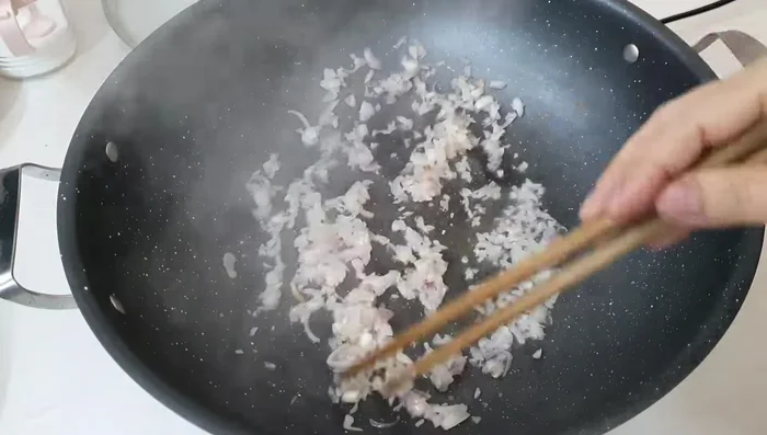 Add the marinated pork to the pan and stir-fry until golden brown.