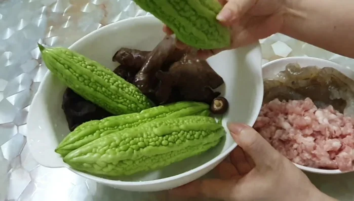 Add water and simmer: Add enough water to cover the ingredients and bring to a boil. Reduce heat and simmer until the bitter melon is tender. (This step is inferred; no exact time is given in the transcript)