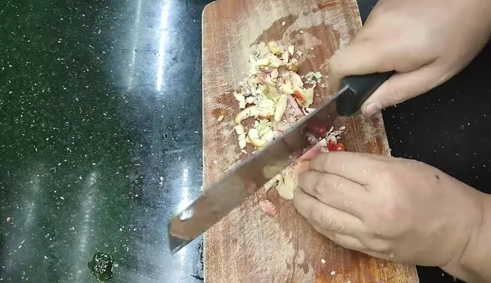 Add oil to the pan and sauté the chopped lemongrass, galangal, shallots, and chili until the edges are browned.