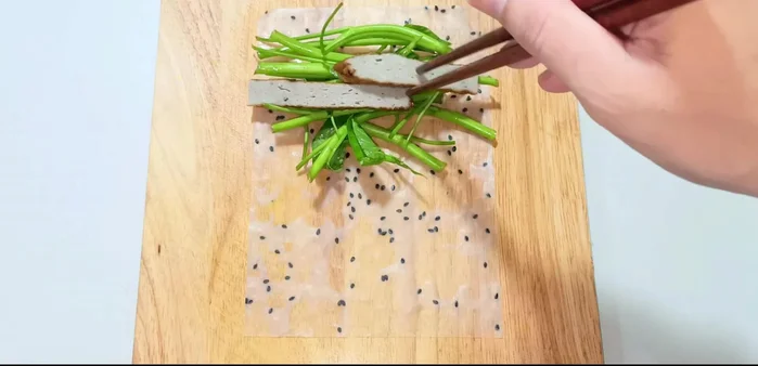 Assemble the rolls: Place water spinach, fried fish cake, and fried onions on the rice paper. Roll tightly.