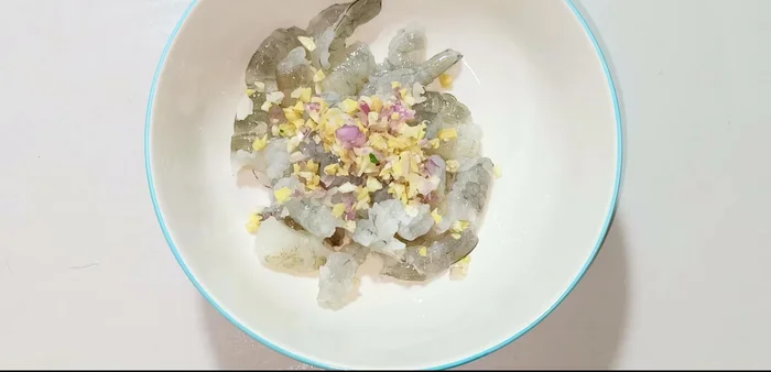 Marinate shrimp with chopped shallots, garlic, ginger, seasoning powder, MSG, sugar, pepper, and fish sauce for 15 minutes. Cut shrimp in half if desired. (198.959)