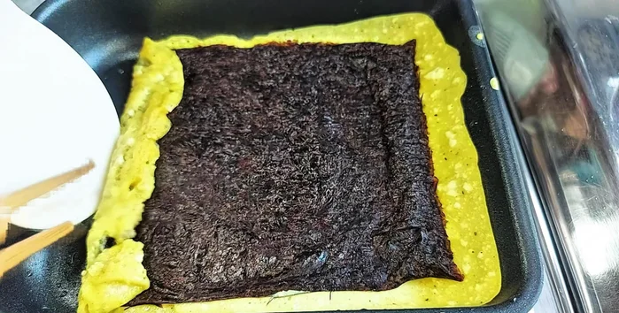Carefully roll the seaweed and egg layer tightly together.