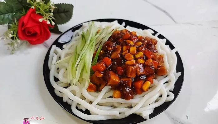 Serve the rice noodles on a plate, top with the vegetable sauce and shredded cucumber.