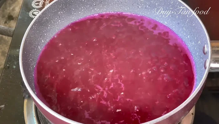 Make purple rice cake batter: Bring 450ml purple leaf water to a boil, add 200g Banh Asian flour, stir constantly until boiling, then cook for 1 minute and turn off heat. Cover to let it expand for 15-20 minutes.