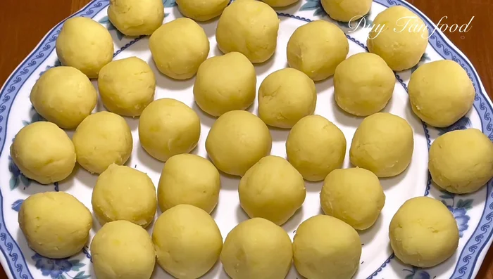 Shape the rice cakes: Divide the mung bean filling into 20g balls. Take a 40g portion of the dough, flatten it, enclose the filling and roll it into a ball. Place into small oiled bowls.