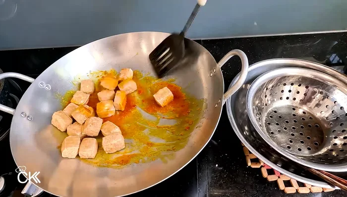 Add the fried tofu to the satay sauce and stir to coat evenly. Cook for 2-3 minutes, until the tofu absorbs the sauce.