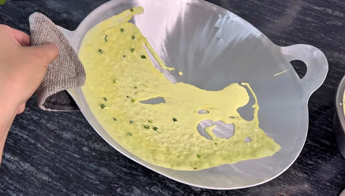 Pour batter onto the hot pan and spread evenly to cook the pancake.