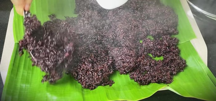 Spread the cooked sticky rice thinly on a banana leaf-lined tray to cool.