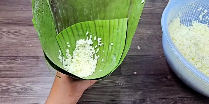 Place a small amount of sticky rice on the banana leaf, add a mung bean ball, and top with more sticky rice.