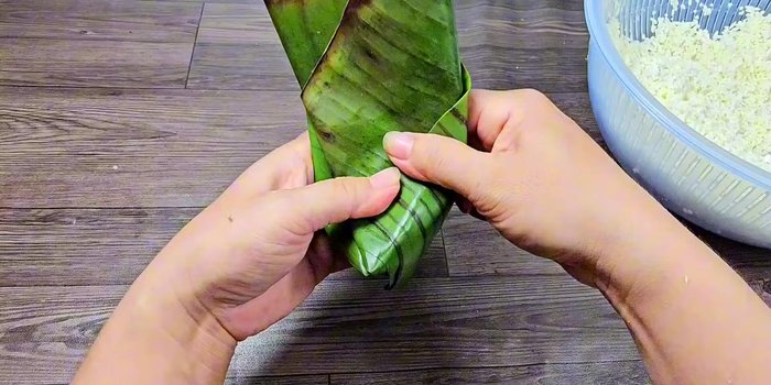 Wrap the sticky rice and filling in the banana leaf, forming a triangle. Tie loosely with string.