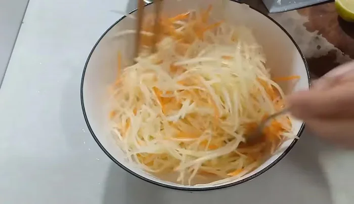 Add the grated papaya and carrots to the dressing. Mix well and let it sit for about 10 minutes for the flavors to meld.
