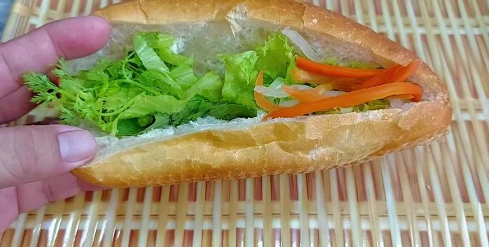 Cut the bread in half and layer with vegetables, pickles, cucumber, and the green bean patties.