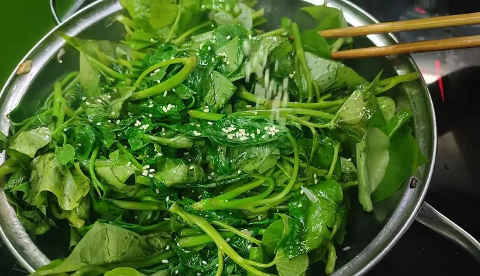 Add sweet potato leaves (or other vegetables) to the wok and stir-fry.