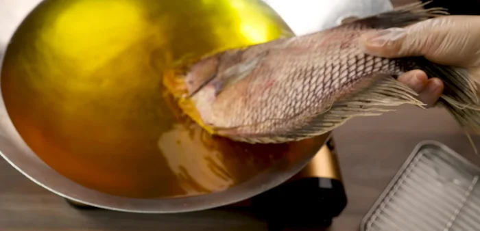 Fry the fish: Fry for about 20-25 minutes, ensuring the fish is evenly coated in oil, turning occasionally to achieve even browning. Use a spoon to baste the fish with oil if necessary to prevent the scales from peeling off.