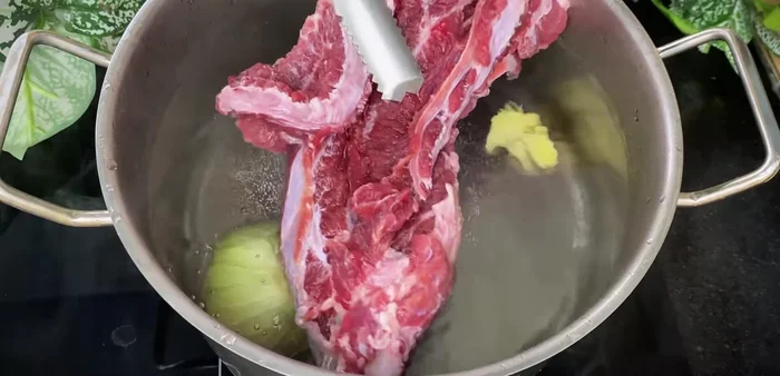 In a separate pot, boil water with onions, ginger, and washed beef brisket, honeycomb, sugarcane leaves, and bag leaves.