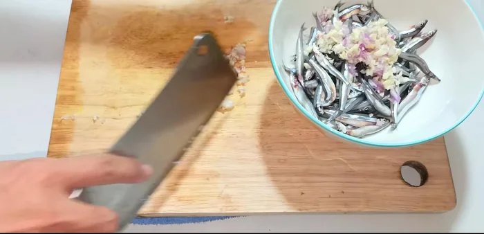 Marinate the anchovies with half of the chopped shallots and garlic, seasoning powder, MSG, ground pepper, sugar, and fish sauce for 15 minutes.